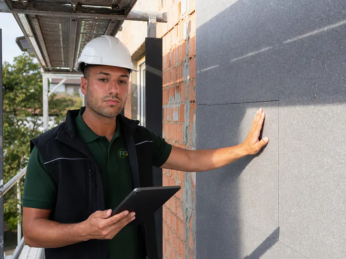 Energieberater prüft die Dämmfassade eines Hauses während der Bauphase
